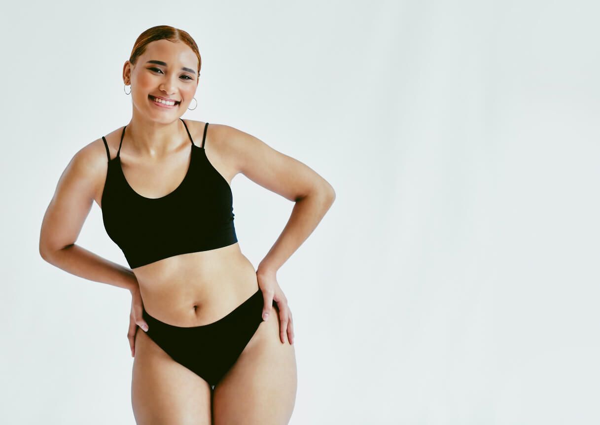 Smiling person in black swimwear against white background.
